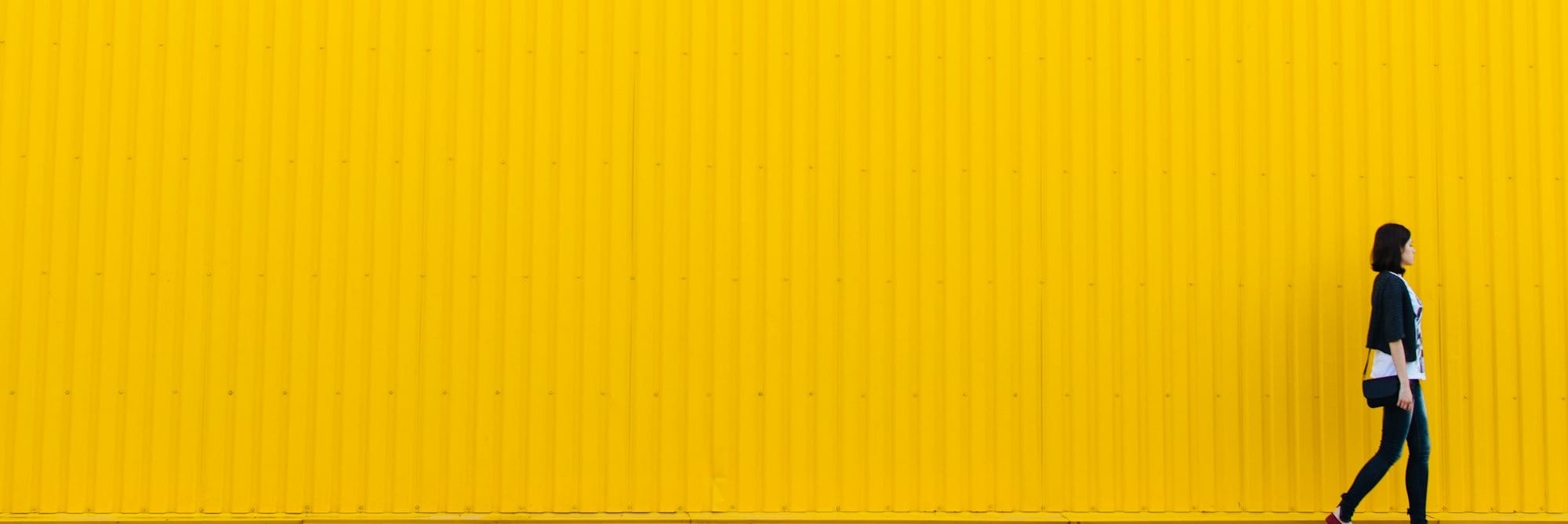 woman wearing black top standing near yellow wall